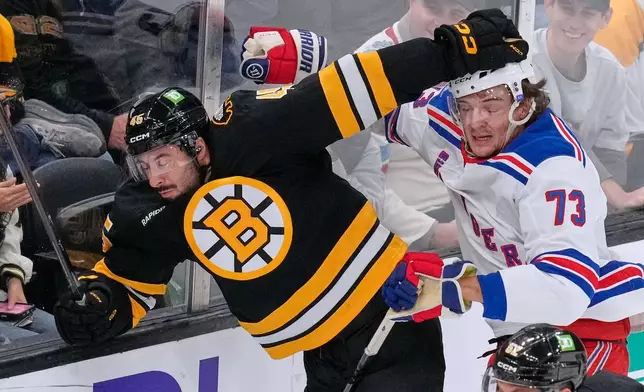 Boston Bruins' Jonathan Aspirot, left, is knocked into the glass by New York Rangers' Matt Rempe (73) during the first period of a NHL hockey game, Tuesday, Sept. 29, 2026, in Boston. (AP Photo/Charles Krupa).