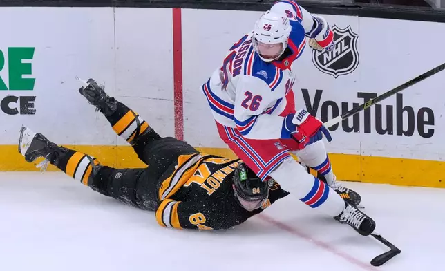 Boston Bruins' Tanner Jeannot, left, is knocked to the ice by New York Rangers' Marcus Pettersson (26) during the first period of a NHL hockey game, Tuesday, Sept. 29, 2026, in Boston. (AP Photo/Charles Krupa)