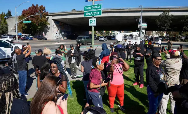 FILE - People take pictures and gather beneath a new sign during a street renaming ceremony for Tupac Shakur in Oakland, Calif., Nov. 3, 2023. (AP Photo/Eric Risberg, File)