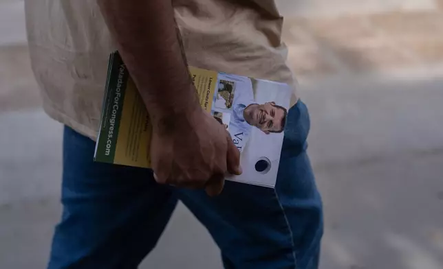 Volunteer Jesus Hernandez carries campaign door hangers while canvassing for U.S. Rep. David Valadao, R-Calif., in Hanford, Calif., Friday, Aug. 21, 2026. (AP Photo/Jae C. Hong)