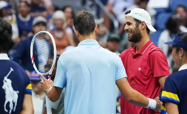 Alexander Blockx, of Belgium, left, meets Karen Khachanov, of Russia, at the net after Blockx was forced to retire due to an apparent injury during the quarterfinal round of the U.S. Open tennis championships, Wednesday, Sept. 9, 2026, in New York. (AP Photo/Kirsty Wigglesworth)