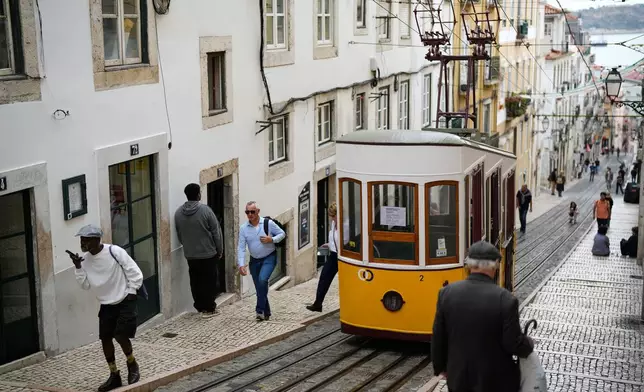 FILE - People walk past a parked Bica funicular in Lisbon, out of service after another streetcar derailed and crashed in the Portuguese capital killing multiple people and injuring several others, Oct. 30, 2025. (AP Photo/Armando Franca, File)