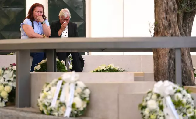 People react during the inauguration of a memorial to the 16 people killed in the derailment and crash of Lisbon's Glória funicular, an iconic streetcar, on the first anniversary of the accident, Thursday, Sept. 3, 2026. (AP Photo/Armando Franca)