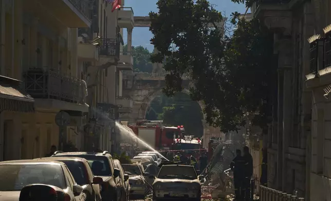 Firefighters work at the scene following a powerful blast that caused a building to collapse and injured at least two people in Athens' Plaka district, with the ancient Hadrian's Arch in the background, Friday, Sept. 25, 2026. (AP Photo/Petros Giannakouris)