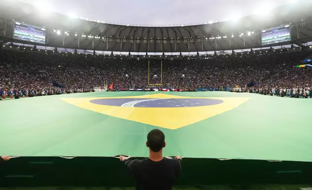 Crews hold a Brazilian flag on the field before an NFL football game between the Dallas Cowboys and the Baltimore Ravens in Rio de Janeiro, Sunday, Sept. 27, 2026. (AP Photo/Fernando Llano)