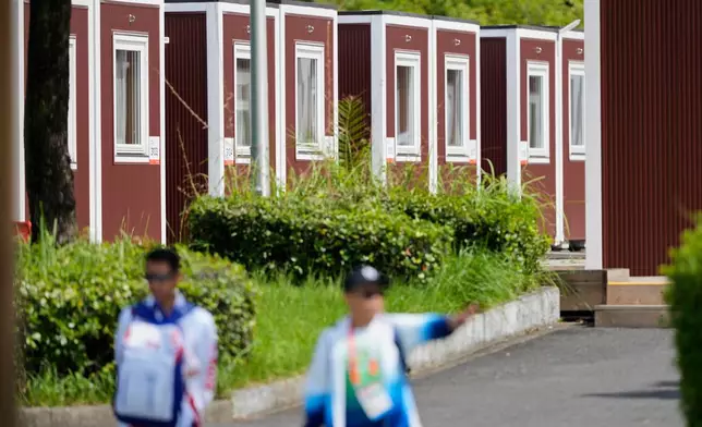 Officials stand outside the athletes accommodation huts at the Athletes Village ahead of the Asian Games Nagoya, Japan, Friday, Sept. 18, 2026. (AP Photo/Dita Alangkara)