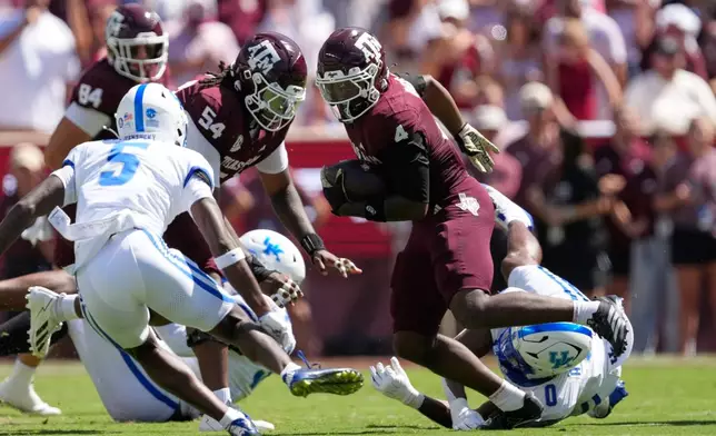 Texas A&M's Rueben Owens II (4) runs for a gain as Kentucky's Bo Barnes (0) and Jordan Castell (5) defend during the first half of an NCAA college football game Saturday, Sept. 19, 2026, in College Station, Texas. (AP Photo/David J. Phillip)