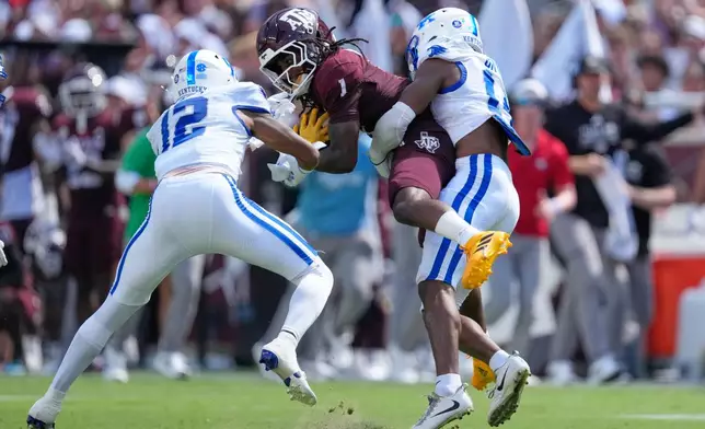 Texas A&M wide receiver Mario Craver (1) is tackled by Kentucky's Ty Bryant (14) and Hasaan Sykes (12) during the first half of an NCAA college football game Saturday, Sept. 19, 2026, in College Station, Texas. (AP Photo/David J. Phillip)