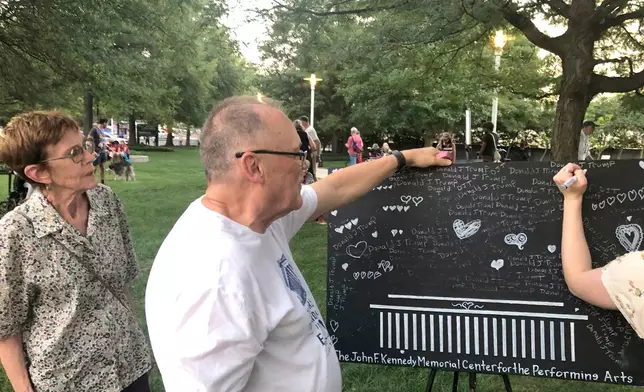 Bud Wilkinson, a member of the local art community, offers protesters at the John F. Kennedy Center for the Performing Arts a chance to erase the President's name and replace it with hearts, Friday, Sept. 18, 2026, in Washington. (AP Photo/Gary Fields)