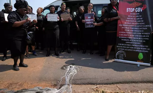 Members of a women's church group sing next to a melted candle as they pay their respects at the site where the body of a woman was discovered the previous week, in Kempton Park, South Africa, east of Johannesburg, Thursday, Sept. 17, 2026. (AP Photo/Themba Hadebe)