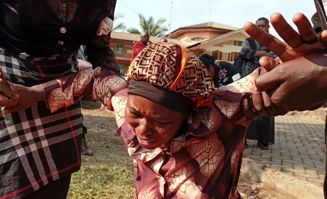 A woman reacts while attending a funeral ceremony for school children who died in a fire that swept through two schools in the city of Bukavu, eastern Congo, Monday, Sept. 14, 2026. (AP Photo/Janvier Barhahiga)