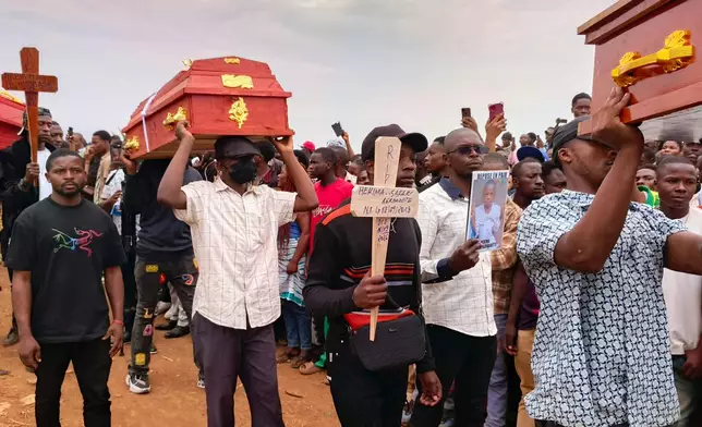 People attend a burial ceremony for school children who died in a fire that swept through two schools in the city of Bukavu, eastern Congo, Monday, Sept. 14, 2026. (AP Photo/Janvier Barhahiga)