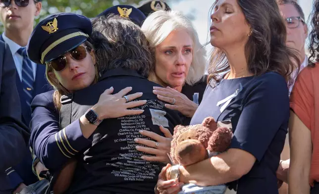 National Transportation Safety Board Chair Jennifer Homendy, center, helps to comfort Christina Stovall, center with back to camera, and Laura Augendre, right, family members of victims of flight 5342, the deadly Jan. 2025 midair collision between an American Airlines plane and a Black Hawk helicopter over the Potomac River, during a news conference on air safety reforms, at the Capitol in Washington, Tuesday, Sept. 15, 2026. (AP Photo/J. Scott Applewhite)
