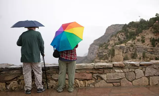 Tourists look over the rim of the Grand Canyon in the rain, Monday, Aug. 31, 2026, in Grand Canyon National Park, Ariz. (AP Photo/Josh Biggs)