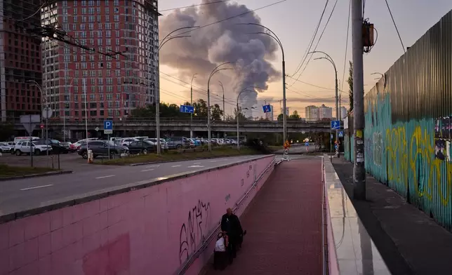 A man walks along an underpass as smoke rises following a Russian missile attack in Kyiv, Ukraine, early Tuesday, Sept. 8, 2026. (AP Photo/Francisco Seco)