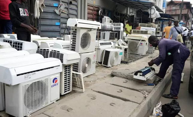 FILE - A man repairs air conditioners on the street in Lagos, Nigeria, July 15, 2024. (AP Photo/Sunday Alamba, File)