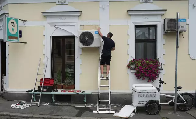 FILE - An worker installs a new air conditioning unit during a hot summer day in Belgrade, Serbia, June 30, 2026. (AP Photo/Darko Vojinovic, File)