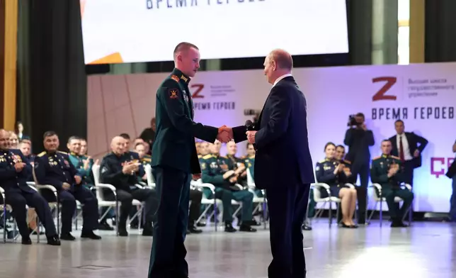 FILE - Russian President Vladimir Putin, right, congratulates Stepan Belov, who was named a Hero of Russia, during a meeting with participants of the "Time of Heroes" project designed to help veterans become government administrators, at a venue outside Solnechnogorsk, Russia, on Friday, June 14, 2024. (Alexander Kazakov, Sputnik, Kremlin Pool Photo via AP)