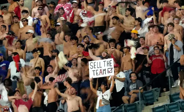 Fans hold up signs and wave shirts during the seventh inning of a baseball game between the Los Angeles Angels and the New York Yankees after Kroenke Sports and Entertainment reached a deal to purchase controlling ownership of the Angels from Arte Moreno, Tuesday, Sept. 1, 2026, in Anaheim, Calif. (AP Photo/Mark J. Terrill)
