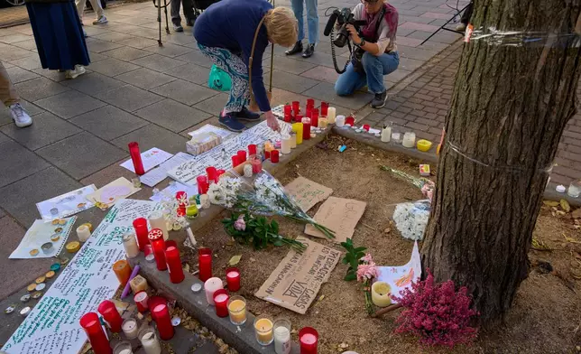A woman places flowers in Madrid, Spain, Thursday, Oct. 8, 2026, near the entrance to the building where Maria del Carmen Abascal, 87, was evicted from her home, sparking nationwide protests. (AP Photo/Manu Fernandez)