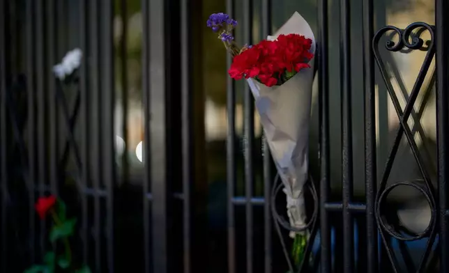 A bouquet of flowers hangs in Madrid, Spain, Thursday, Oct. 8, 2026, on a door at the entrance to the building where Maria del Carmen Abascal, 87, was evicted from her home, sparking nationwide protests. (AP Photo/Manu Fernandez)