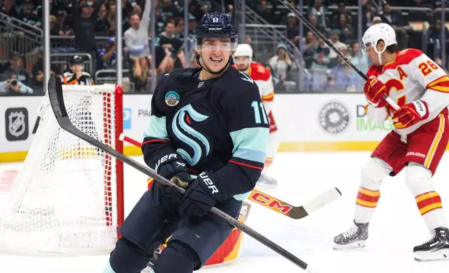 Seattle Kraken right wing Mackie Samoskevich (11) reacts after scoring as Calgary Flames defenseman Zach Whitecloud (28) skates off during the first period of an NHL hockey game Sunday, Oct. 4, 2026, in Seattle. (AP Photo/Jason Redmond)