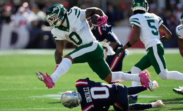 New York Jets running back Braelon Allen (0) leaps over New England Patriots cornerback Christian Gonzalez (0) during the first half of an NFL football game in Foxborough, Mass., Sunday, Oct. 18, 2026. (AP Photo/Charles Krupa)