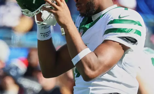 New York Jets quarterback Geno Smith puts on his helmet before an NFL football game against the New England Patriots in Foxborough, Mass., Sunday, Oct. 18, 2026. (AP Photo/Mark Stockwell)