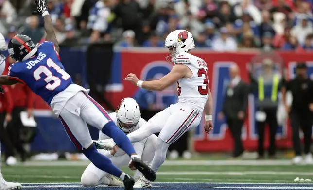 Arizona Cardinals kicker Chad Ryland, right, kicks a 60-yard field goal with the help of Cardinals holder Blake Gillikin (12) as New York Giants cornerback Nic Jones (31) dives for the ball during an NFL football game, in East Rutherford, N.J., Sunday, Oct. 4, 2026. (AP Photo/Adam Hunger)