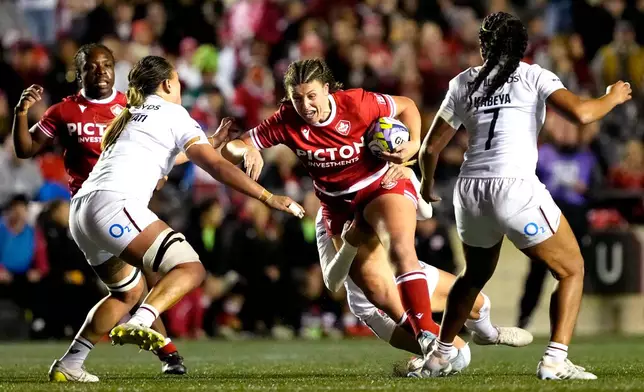Canada's Daleaka Menin, center front , tries to get past England's Maddie Feaunati, front left, and Sadia Kabeya (7) as she is tackled by Zoe Harrison, center back, in the first half of a rugby match in Ottawa, Ontario, Friday, Oct. 23, 2026. (Justin Tang/The Canadian Press via AP)