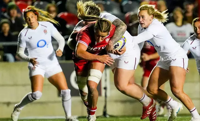 Canada's Sophie de Goede, center front, tries to hold onto the ball against a tackle by England's Hannah Botterman, center back, in the first half of a rugby match in Ottawa, Ontario, Friday, Oct. 23, 2026. (Justin Tang/The Canadian Press via AP)