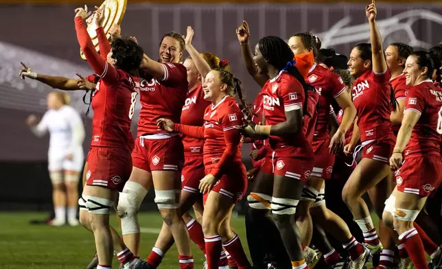 Canada's Sophie de Goede, second from left, holds the Utrecht Shield as the team celebrates after their win over England in a rugby match in Ottawa, Ontario, Friday, Oct. 23, 2026. (Justin Tang/The Canadian Press via AP)
