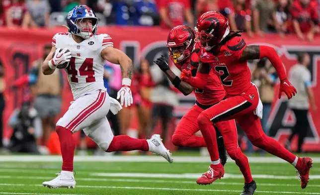 New York Giants running back Cam Skattebo (44) carries the ball with Houston Texans safety Calen Bullock (2) and cornerback Kamari Lassiter, center, defending during overtime in an NFL football game in Houston, Sunday, Oct. 25, 2026. (AP Photo/Gerald Herbert)