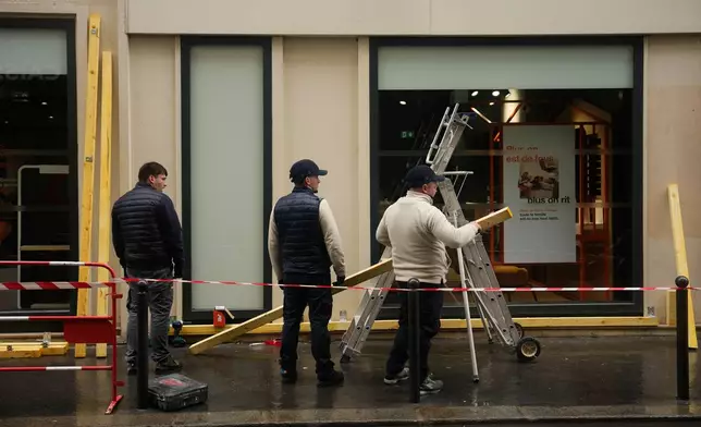 Workers board up a storefront on the eve of a demonstration against rising living costs in Paris, Friday, Oct. 23, 2026. (AP Photo/Teresa Suarez)