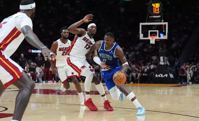 Minnesota Timberwolves guard Anthony Edwards (5) drives past Miami Heat center Bam Adebayo (13) as forward Andrew Wiggins (22) looks on during the second half of an NBA basketball game, Wednesday, Oct. 21, 2026, in Miami. (AP Photo/Rebecca Blackwell)