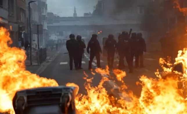French policemen stand in front of burning garbage as high school students protest to demand more resources, in Lille, France, Thursday, Oct. 1, 2026. (AP Photo/Jean-Francois Badias)