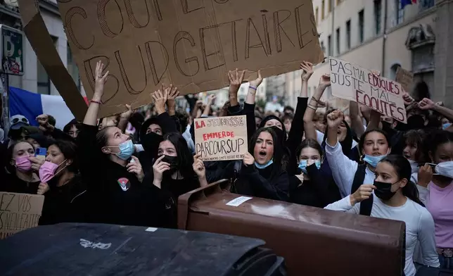 Students hold a sign reading "Stop budget cuts" as they protest against under-resourced schools in front of a high school blockade, in Lyon, France, Friday, Oct. 2, 2026. (AP Photo/Laurent Cipriani)