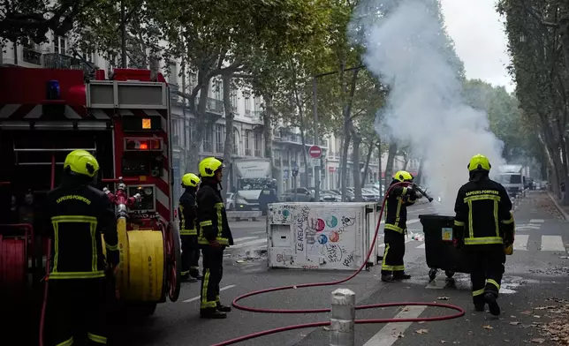Firefighters extinguish a fire as students protest against under-resourced schools in Lyon, France, Friday, Oct. 2, 2026. (AP Photo/Laurent Cipriani)