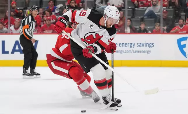 Detroit Red Wings defenseman Moritz Seider (53) knocks the puck off the stick of New Jersey Devils right wing Anthony Mantha (39) in the first period of an NHL hockey game Tuesday, Oct. 13, 2026, in Detroit. (AP Photo/Paul Sancya)