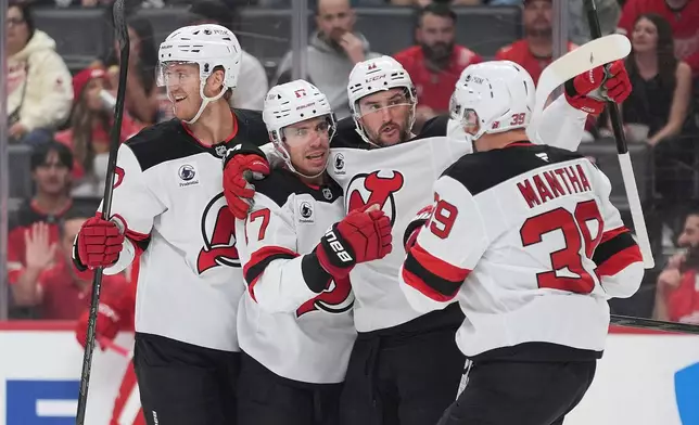New Jersey Devils center Evan Rodrigues, second from left, celebrates his goal against the Detroit Red Wings in the first period of an NHL hockey game Tuesday, Oct. 13, 2026, in Detroit. (AP Photo/Paul Sancya)