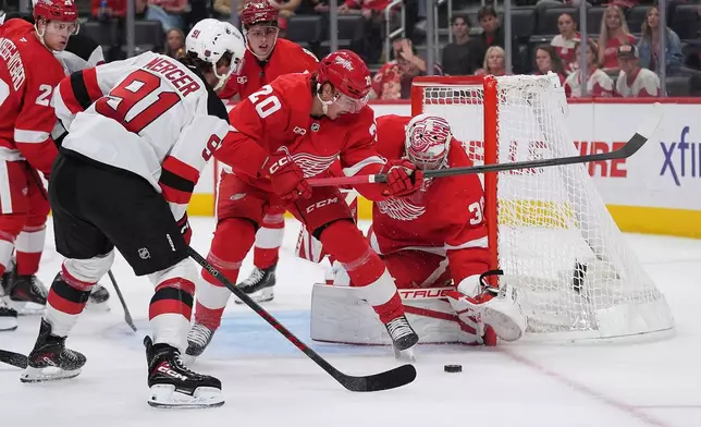 Detroit Red Wings goaltender John Gibson (36) stops a New Jersey Devils center Dawson Mercer (91) shot as Albert Johansson (20) defends in the first period of an NHL hockey game Tuesday, Oct. 13, 2026, in Detroit. (AP Photo/Paul Sancya)