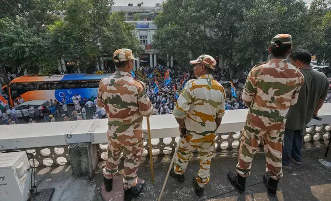 Security personnel keep vigil from the rooftop of a building as members of the student wing of India's Congress party and other protesters gather to start a march demanding the resignation of the country's election chief Gyanesh Kumar, in New Delhi, India, Thursday, Oct. 8, 2026. (AP Photo/Manish Swarup)