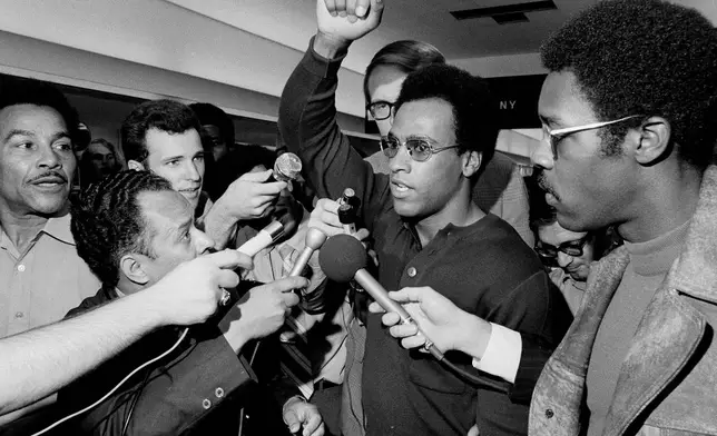 FILE - Huey Newton, Black Panther Party minister of defense, raises his arm as he is surrounded by the press at Philadelphia's International Airport, Sept. 4, 1970, upon his arrival for a convention in Philadelphia. (AP Photo/Rusty Kennedy, File)