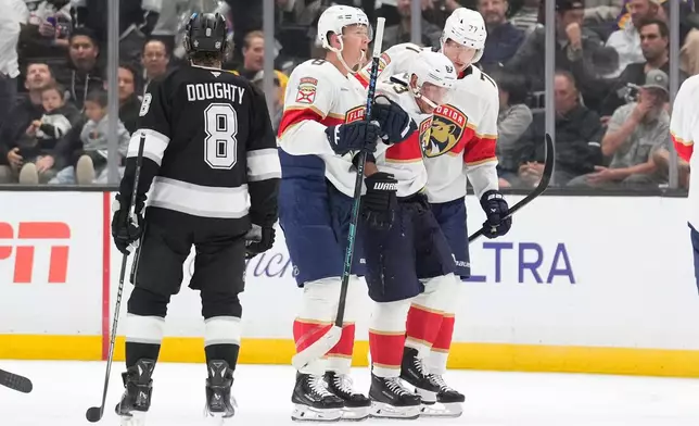 Florida Panthers left wing Brad Marchand, second from right, is helped off the ice by left wing Brady Tkachuk, second from left, and defenseman Niko Mikkola after he was injured as Los Angeles Kings defenseman Drew Doughty looks on during the second period of an NHL hockey game Tuesday, Oct. 6, 2026, in Los Angeles. (AP Photo/Mark J. Terrill)