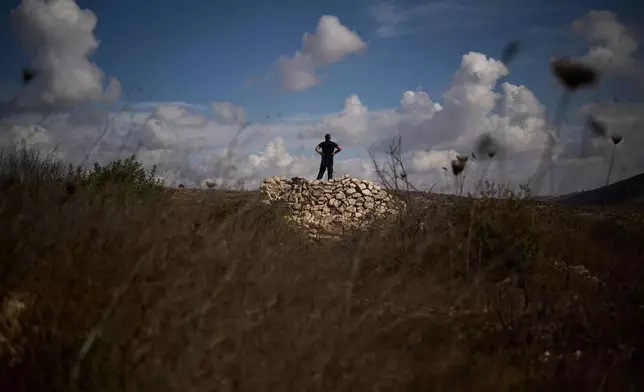 A Palestinian checks for the presence of Israeli settlers as he takes part in a community action to clear the area around olive trees in preparation for the upcoming harvest season on the outskirts of the West Bank town of Birzeit, Friday, Oct. 2, 2026, in an area that, according to residents, they were unable to access last year due to Israeli army restrictions and settler attacks. (AP Photo/Leo Correa)