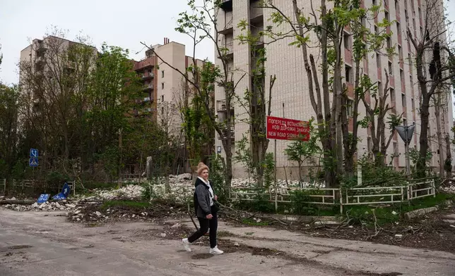 A local woman walks in front of a residential building damaged in a Russian attack during a local ceasefire related to a humanitarian aid mission in Oleshky, in Kherson, Ukraine, Wednesday, Oct. 28, 2026. (AP Photo/Evgeniy Maloletka)