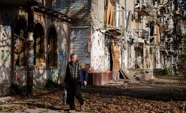 A man walks in front of a residential building damaged in a Russian attack during a local ceasefire related to a humanitarian aid mission in Oleshky, in Kherson, Ukraine, Wednesday, Oct. 28, 2026. (AP Photo/Evgeniy Maloletka)