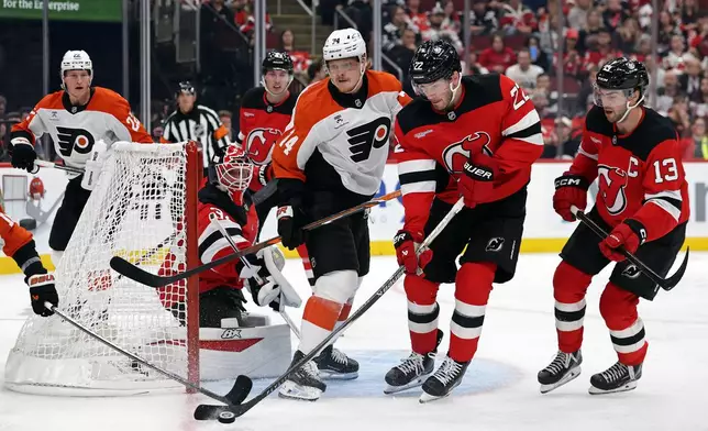 New Jersey Devils defenseman Brett Pesce (22), second from right, clears the puck in front of Philadelphia Flyers right wing Owen Tippett (74) during the third period of an NHL hockey game Thursday, Oct. 1, 2026, in Newark, N.J. (AP Photo/Adam Hunger)