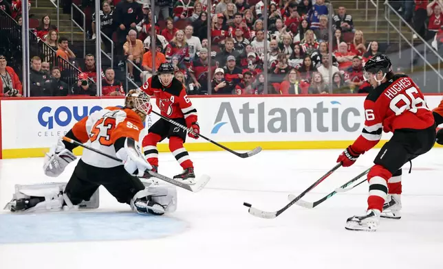 New Jersey Devils center Jack Hughes (86) shoots the winning goal past Philadelphia Flyers goaltender Joseph Woll, left, during overtime of an NHL hockey game Thursday, Oct. 1, 2026, in Newark, N.J. (AP Photo/Adam Hunger)