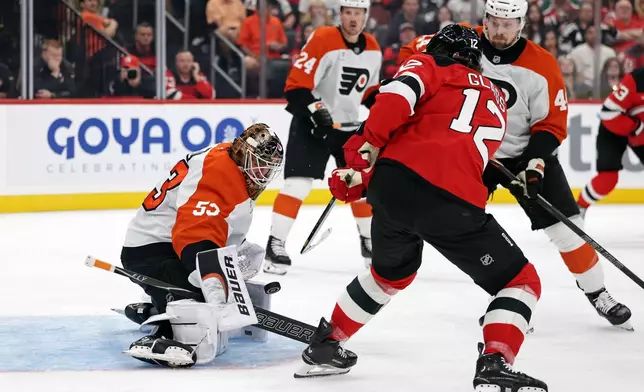 Philadelphia Flyers goaltender Joseph Woll, left, makes a save against New Jersey Devils center Cody Glass (12) during the second period of an NHL hockey game Thursday, Oct. 1, 2026, in Newark, N.J. (AP Photo/Adam Hunger)